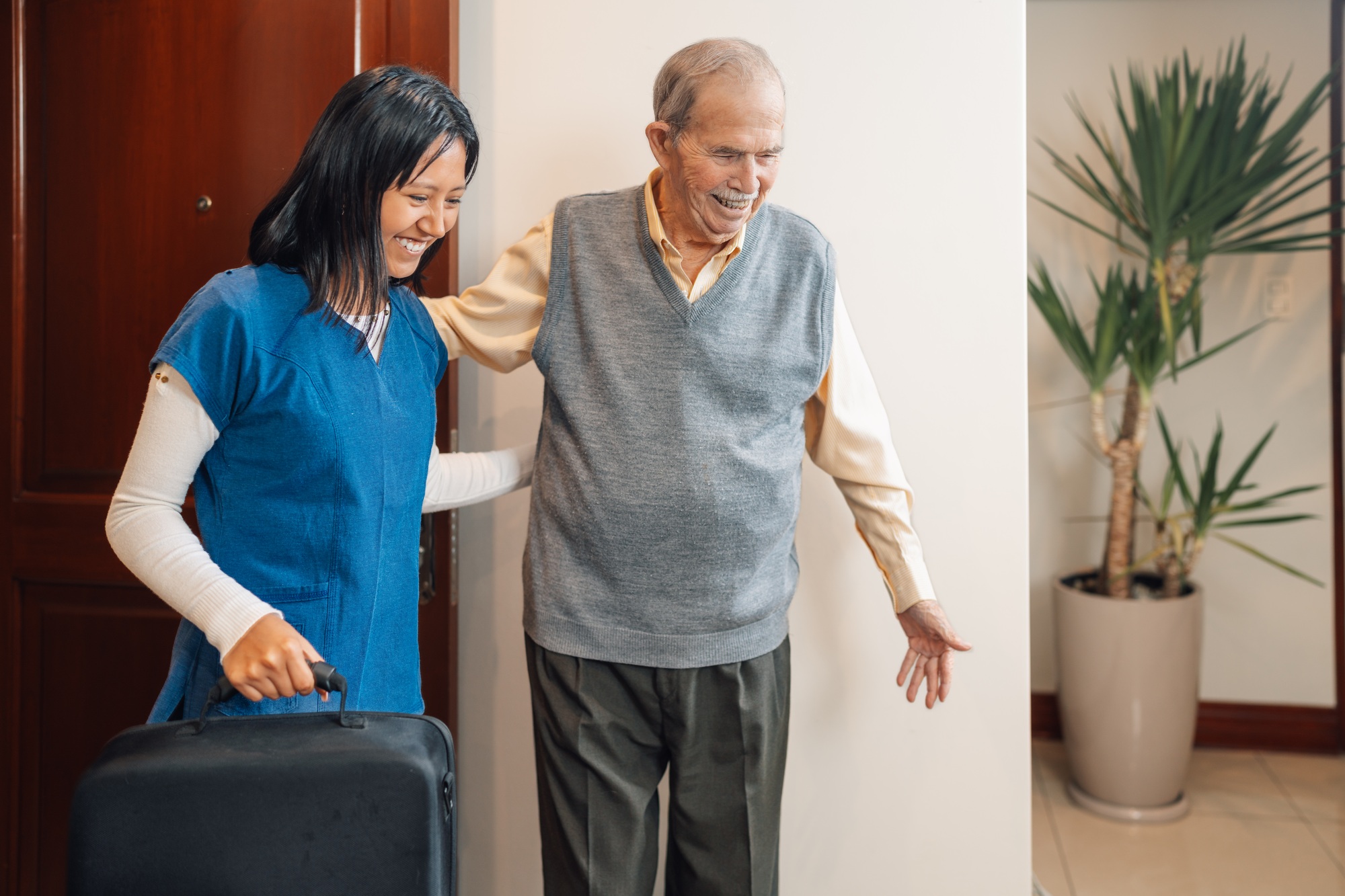 Nurse assisting an elder man visiting him at home